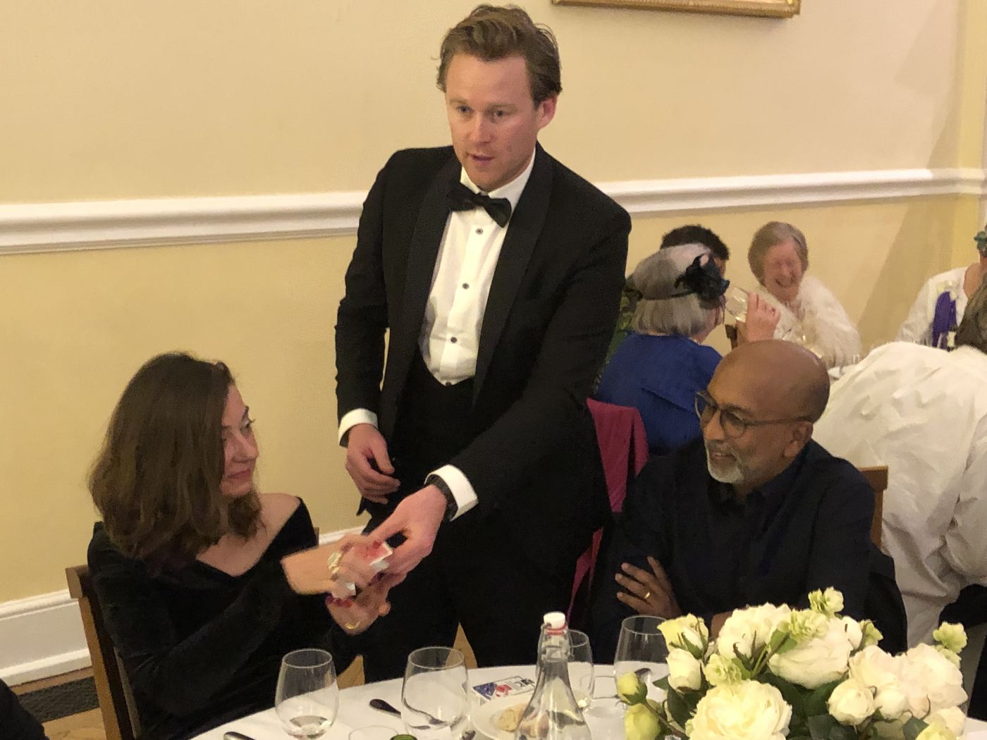 A guest selecting a playing card during close-up magic at a black-tie dinner