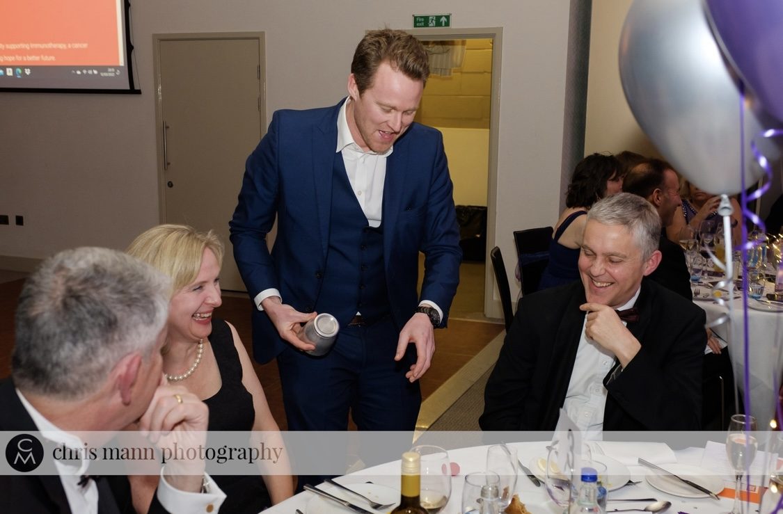 Guests at a round table watching close-up magic during a celebration dinner