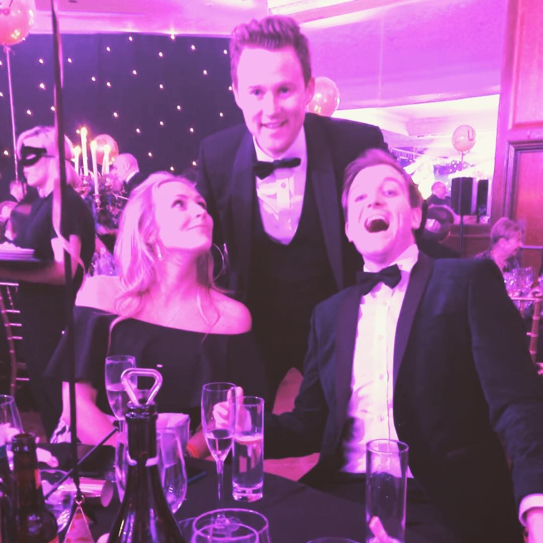 Guests at a black-tie corporate dinner laughing as a trick is revealed