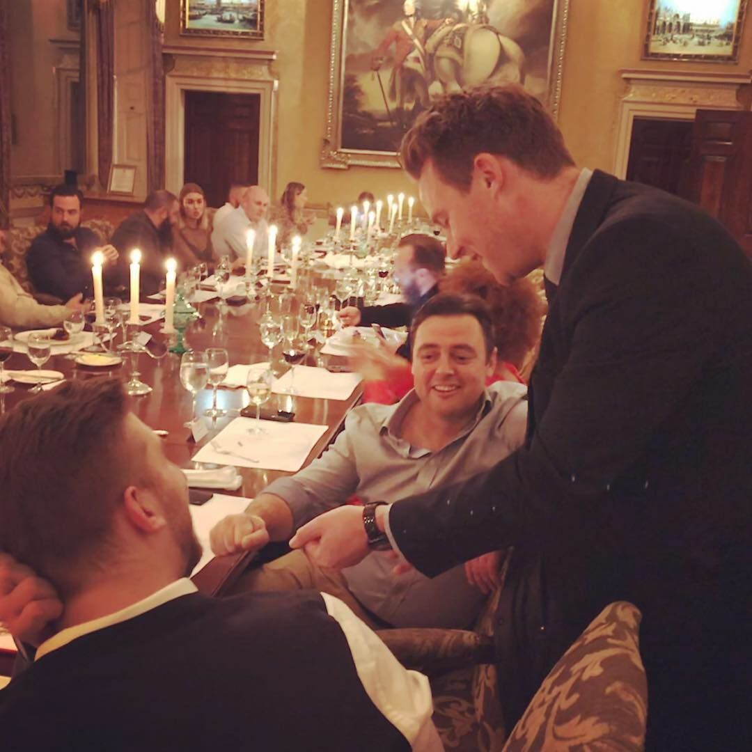 A guest grinning during close-up magic at a candlelit banqueting table