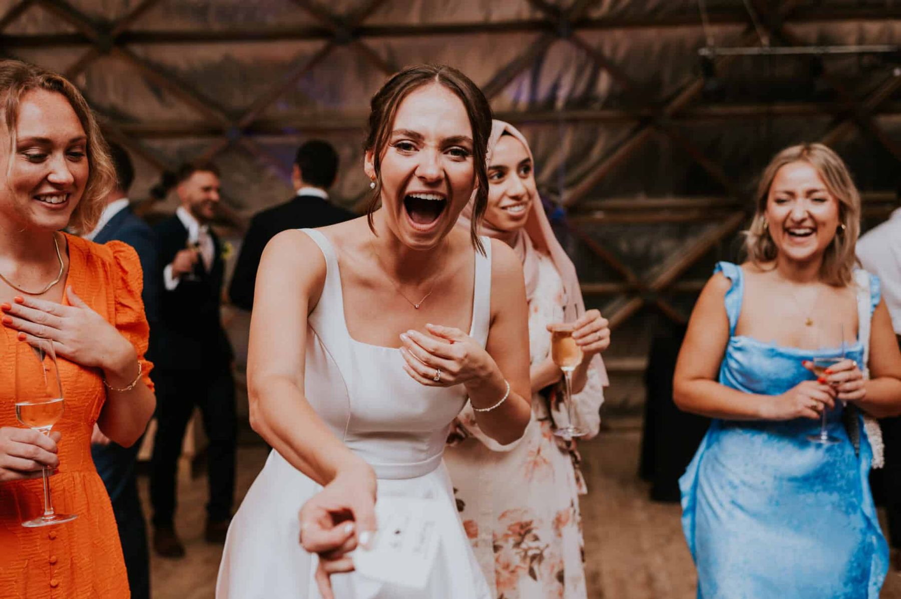 A bride laughing in delighted disbelief during Richard Kettle's close-up magic at her wedding