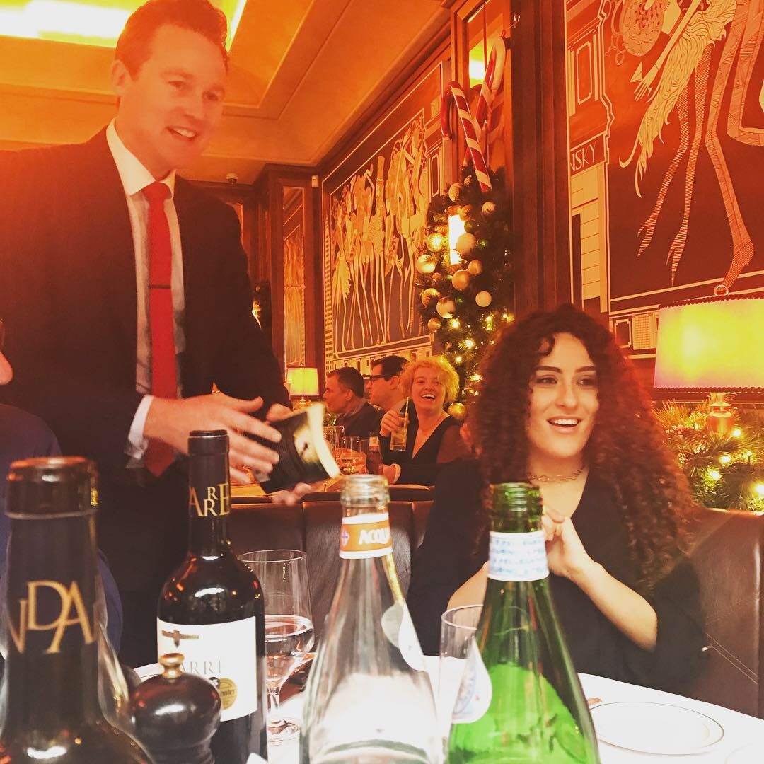 A party guest smiling as Richard Kettle shows her a card at a festive dinner