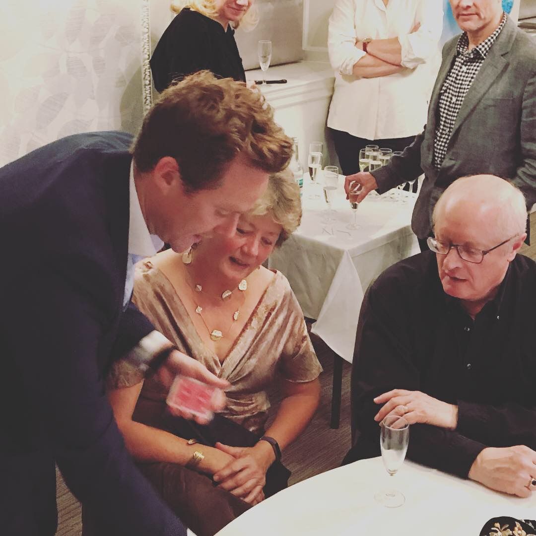 A guest laughing as a chosen card appears during close-up magic at a party