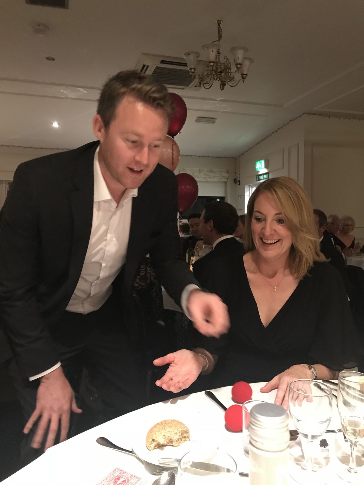 A dinner guest laughing as Richard Kettle reveals a trick at her table