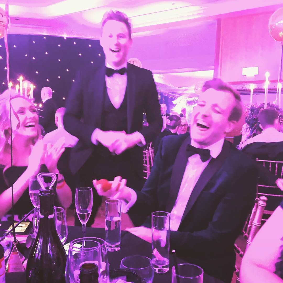 A guest in black tie roaring with laughter at a close-up magic trick