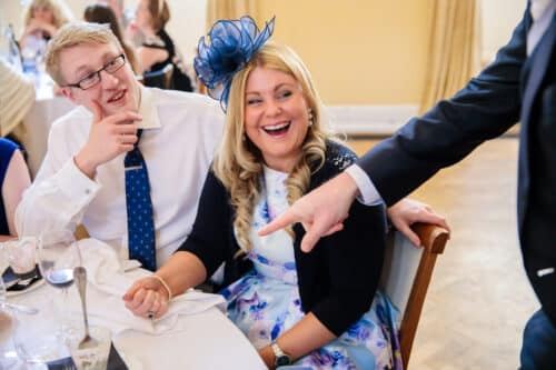 A guest in a fascinator laughing with delight