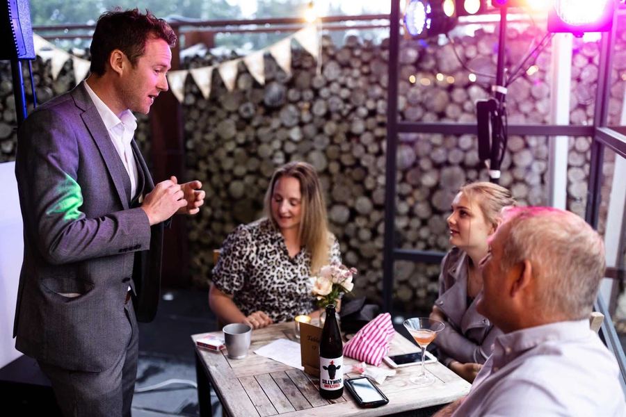 Guests enjoying close-up magic at an evening terrace party