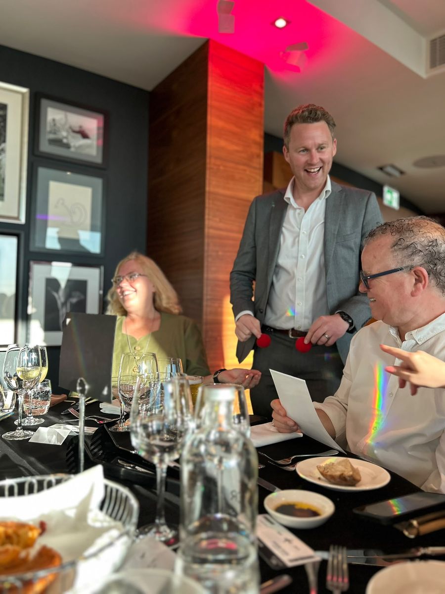 Diners laughing during close-up magic at a restaurant table