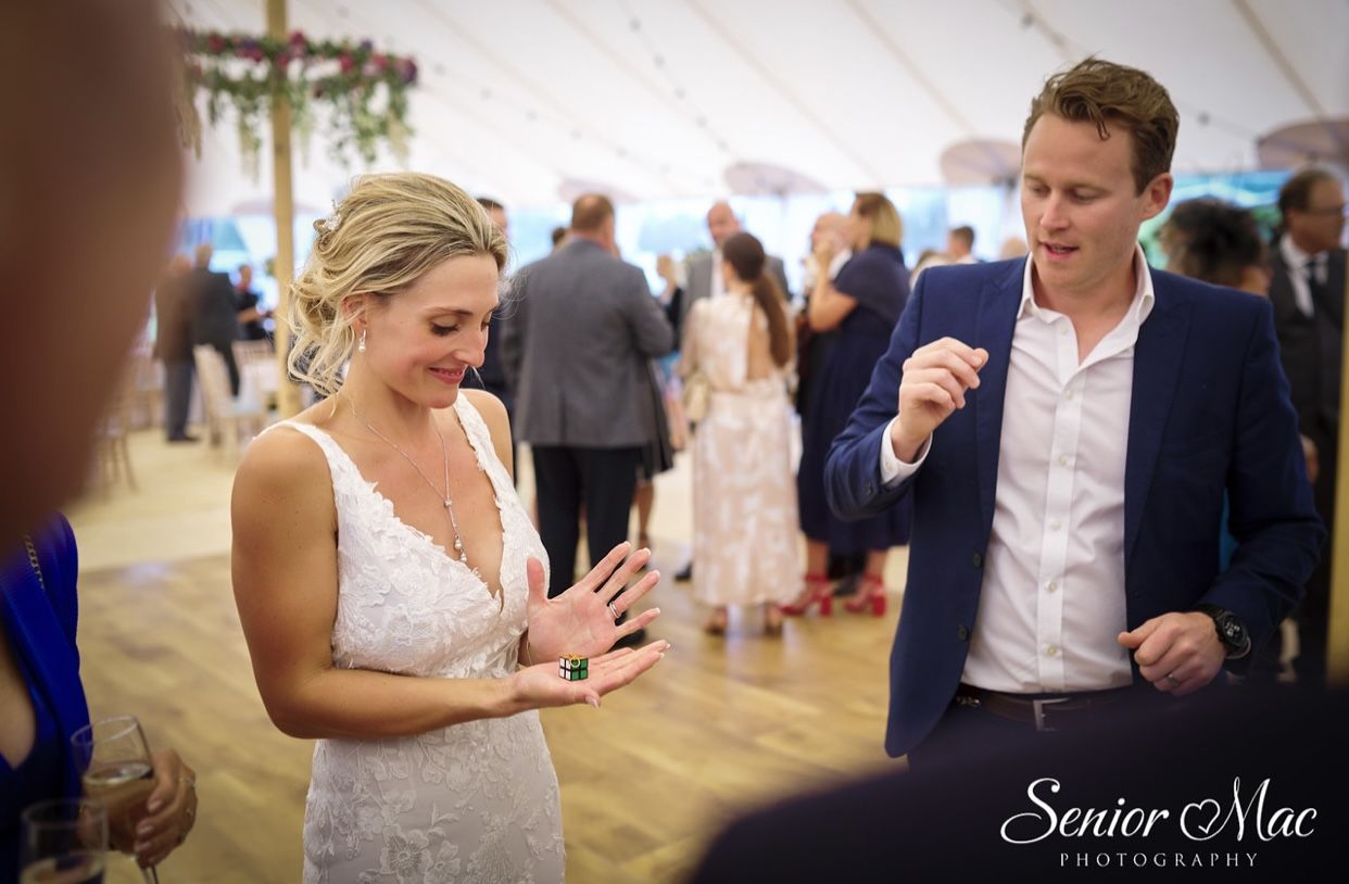 A bride watching close-up magic in her hands at a marquee wedding reception