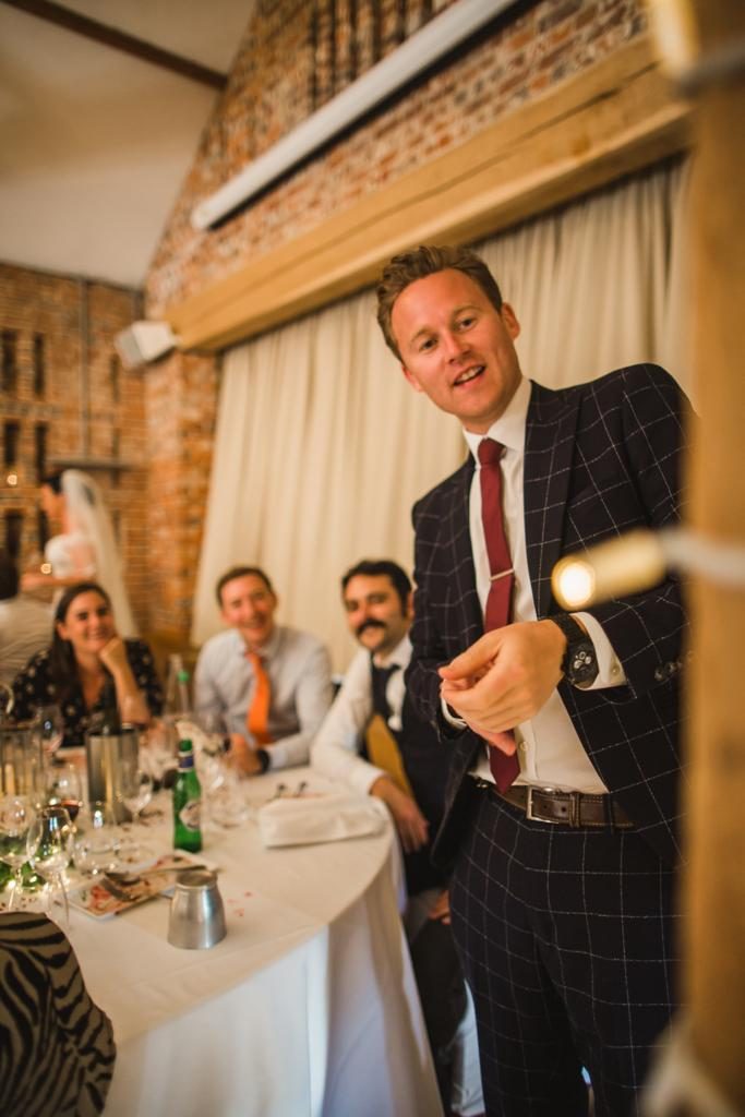 Richard Kettle performing a trick for smiling guests at an evening wedding table