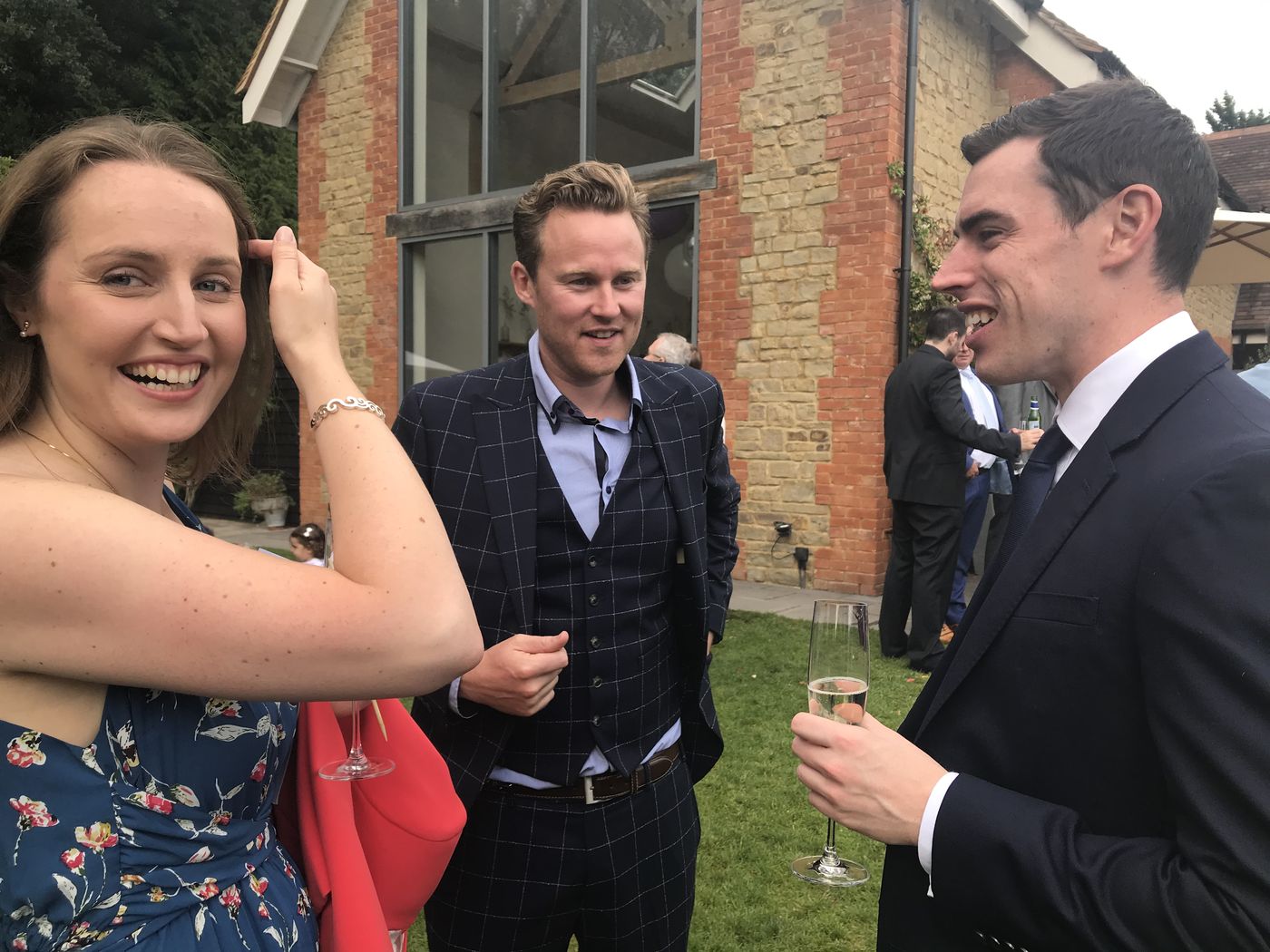 A wedding guest laughing in a garden as Richard Kettle performs close-up magic