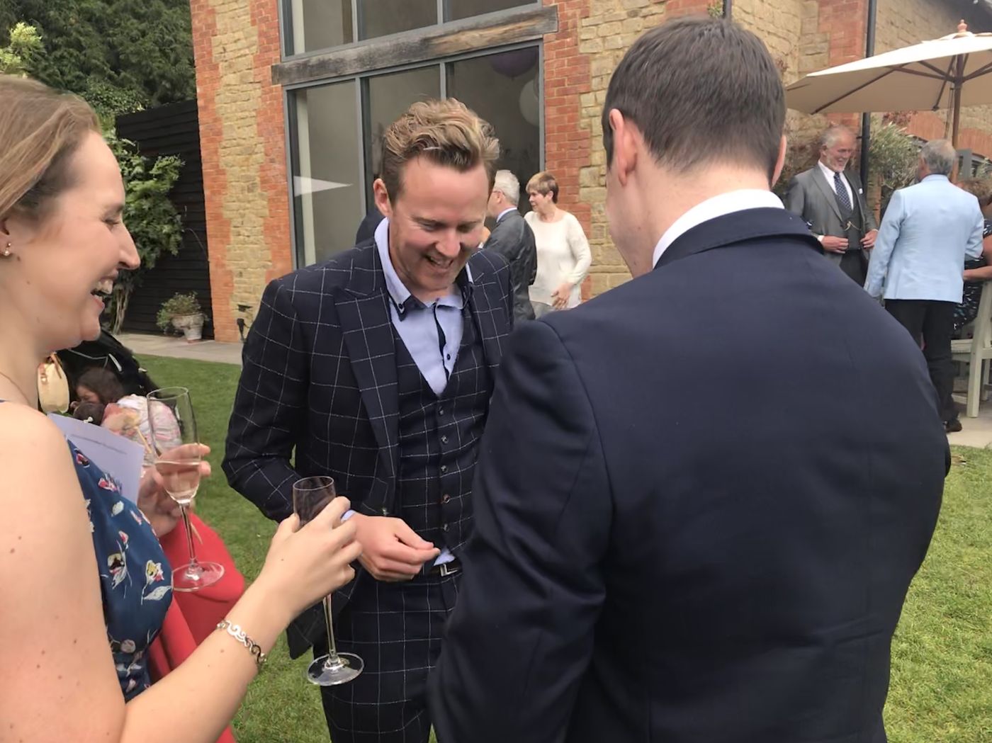 Richard Kettle showing a card to guests at an outdoor wedding reception