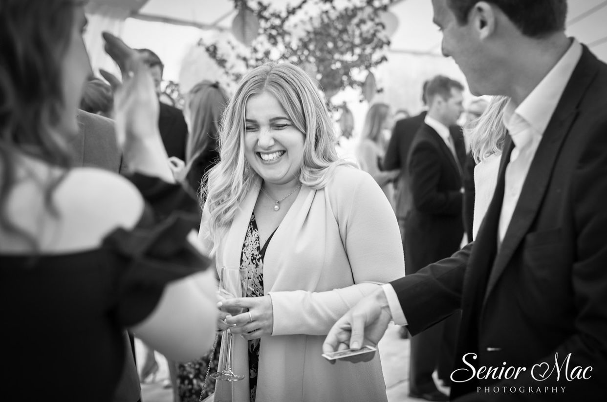 A wedding guest laughing during close-up magic at a drinks reception