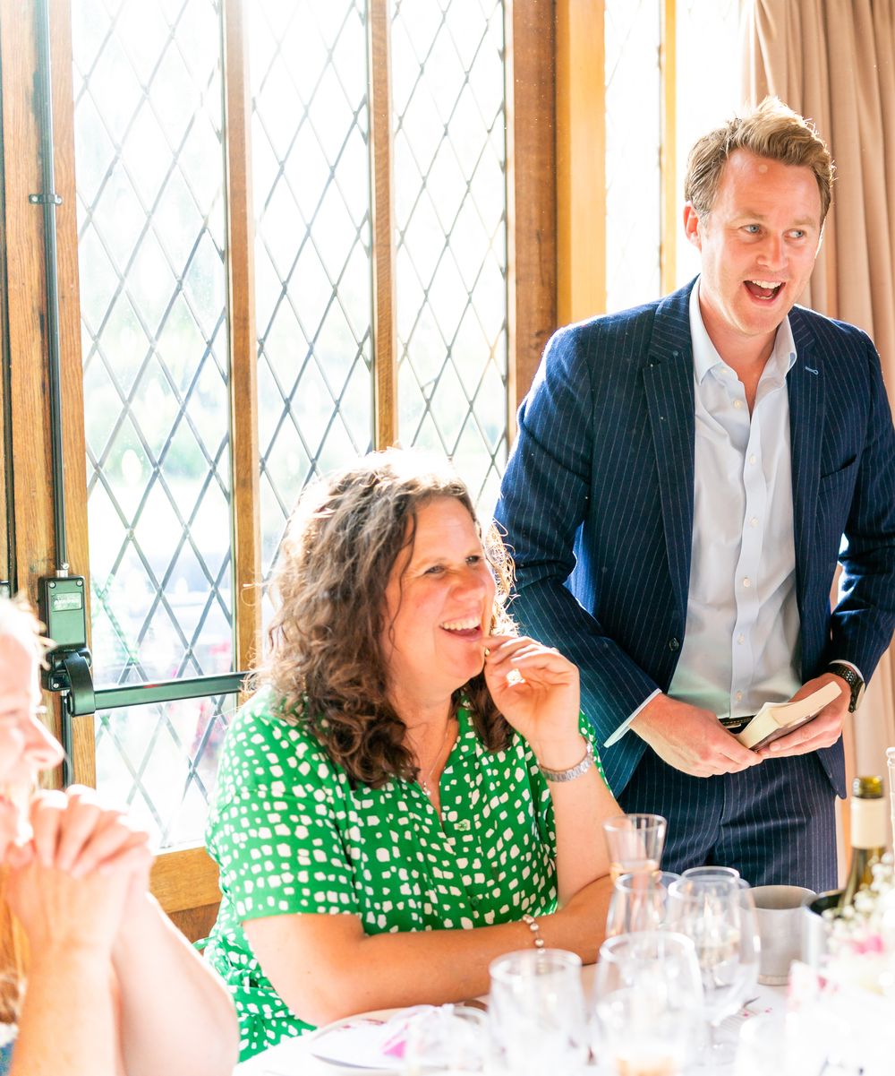 A wedding guest laughing at her table as Richard Kettle reveals a card